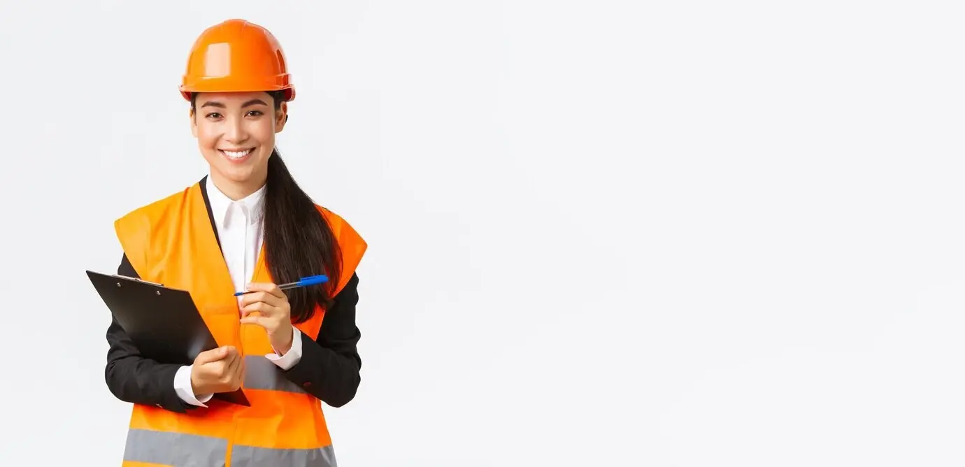 Confident, smiling Asian female construction engineer and industrial professional wearing a safety helmet, visiting a building area for inspection, writing notes on a clipboard, and looking satisfied, against a white background.